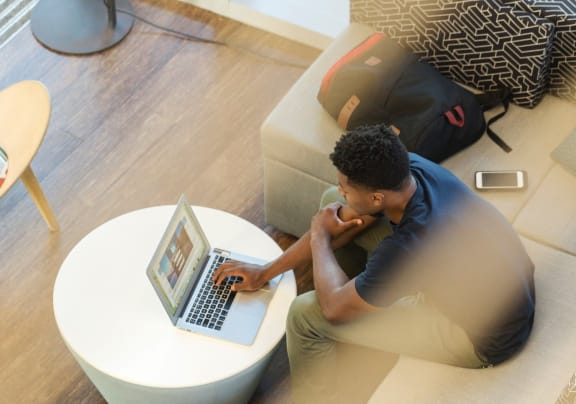 a man sitting on a couch looking at his laptop