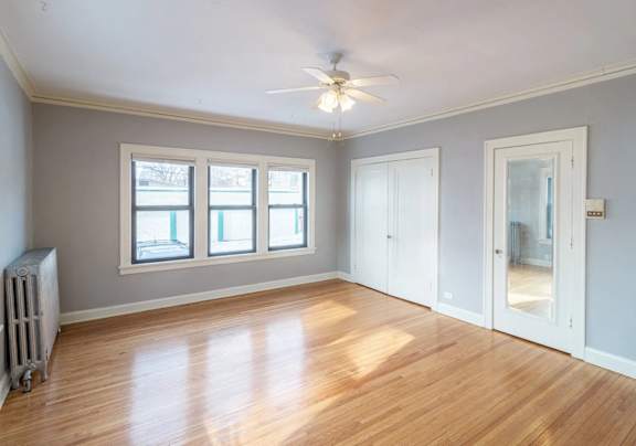 A room with a ceiling fan and a radiator on the floor.