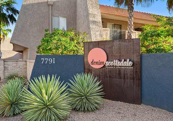 A house with a sign that says "denim scottsdale" in front of it.
