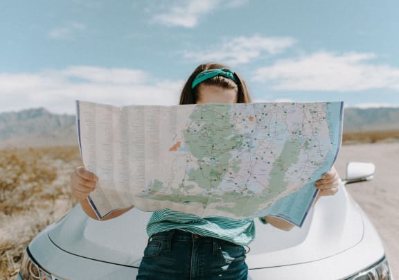 a woman holding a map on top of a car