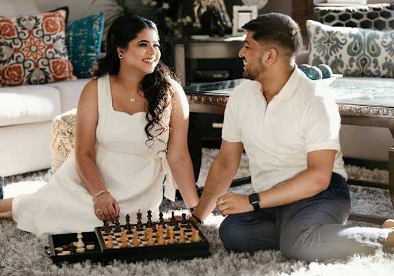 A man and woman sitting on the floor playing a game of chess.