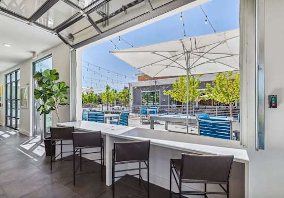 A patio with a table and chairs overlooking a pool.