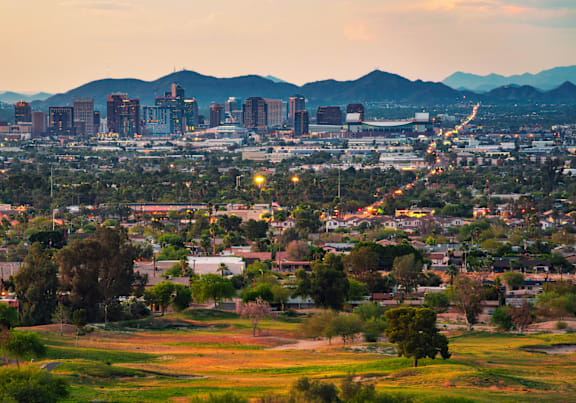 A cityscape with buildings and greenery in the foreground.