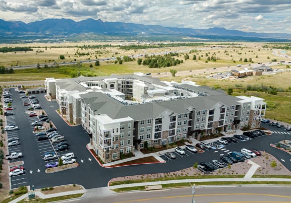 an aerial view of an apartment complex with a parking lot and mountains in the background