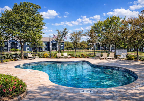 A swimming pool surrounded by a fence and trees.