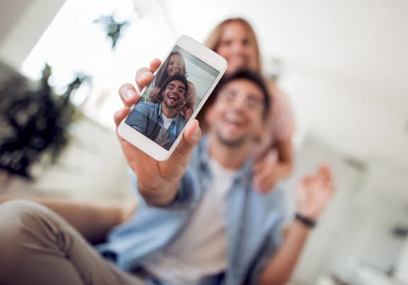 a man holding up a cell phone with his family on it