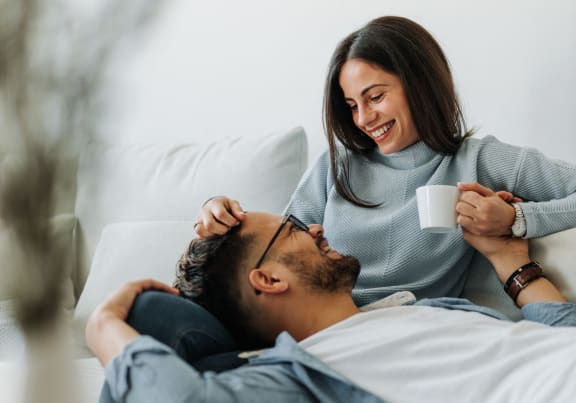 a man laying in bed with a woman holding a cup of coffee