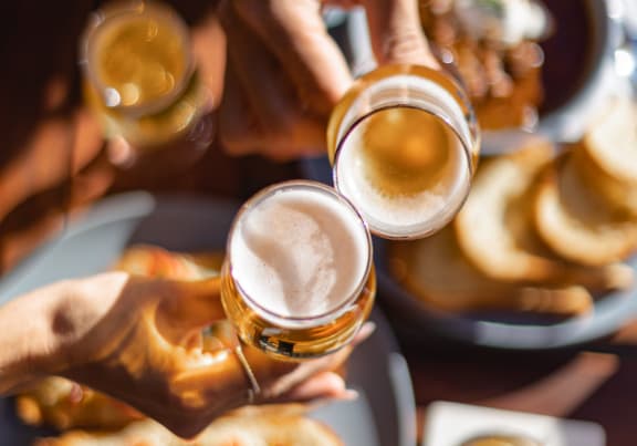 a group of people giving each other a toast with beers in their hands