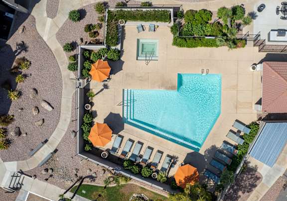 An aerial view of a pool surrounded by orange umbrellas and lounge chairs.
