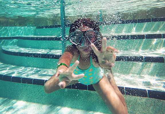 A person in a blue swimsuit is underwater in a pool.