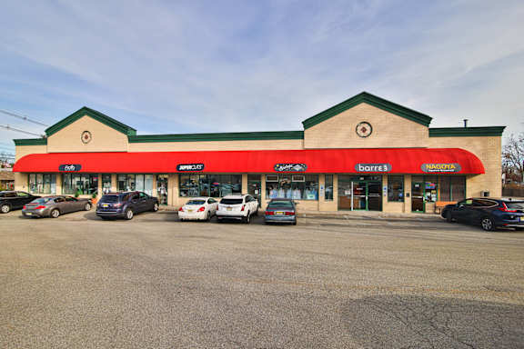 the front of a gas station with cars parked in a parking lot
