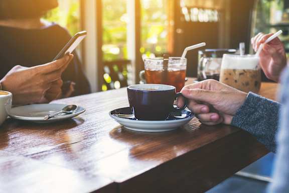 people sitting at a table drinking coffee and using their cell phones