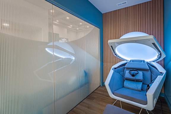 A modern room with a blue chair and a light on the ceiling. at Allure Apartments LLC Apartments, Indiana