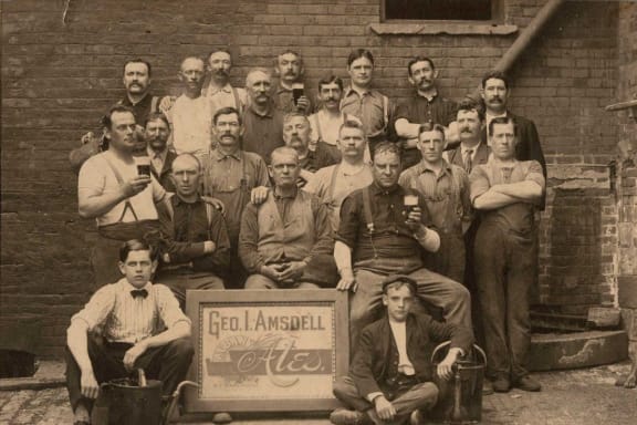 a group of men standing next to each other in front of a brick building