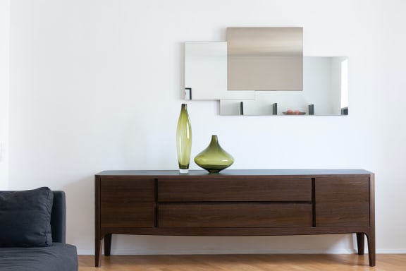 a vase with a green vase on top of a wooden chest of drawers