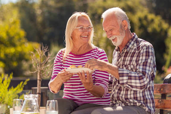 An elderly couple enjoying a meal together outdoors.