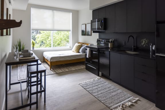 a kitchen and living room with a large window and black cabinets at Shift, Oregon, 97217