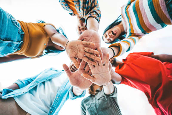 people standing in a circle with their hands together