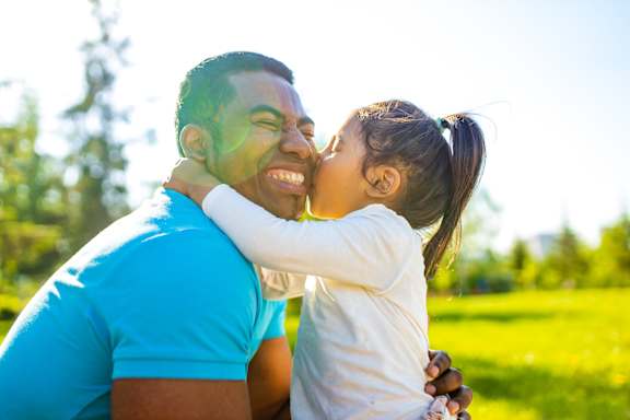 a little girl kissing a man on his face