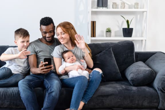a family sitting on a couch while looking at a cell phone