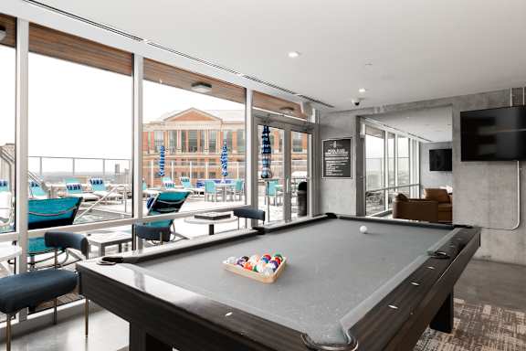 A pool table in a room with a view of the outside.