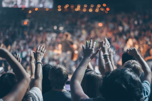 people cheering at a concert with their hands in the air