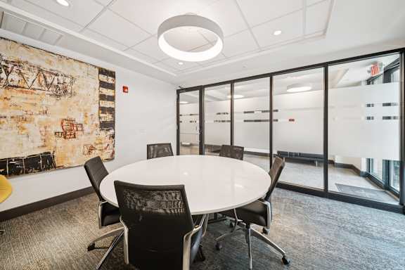 A conference room with a white table and black chairs.