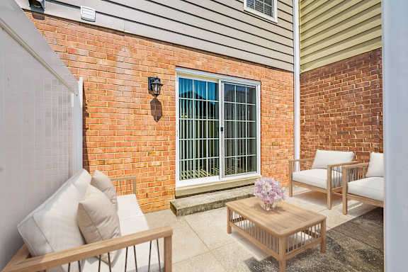 A patio with a table, chairs, and a window with bars.
