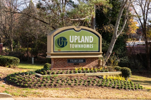 a sign for upland townhomes in front of a tree