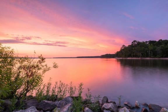 a sunset over a lake with rocks and trees