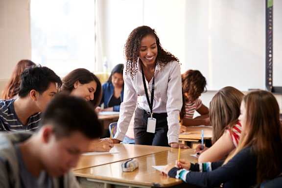 A teacher is standing in front of a classroom full of students.