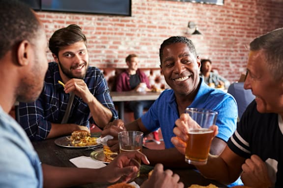 A group of people are enjoying a meal and drinks together in a restaurant.