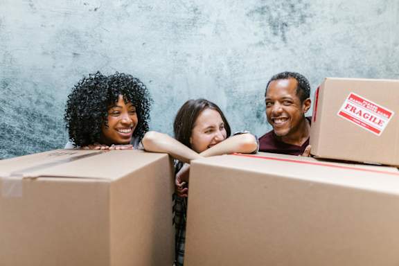 Three people leaning on cardboard boxes with "FRAGILE" labels.