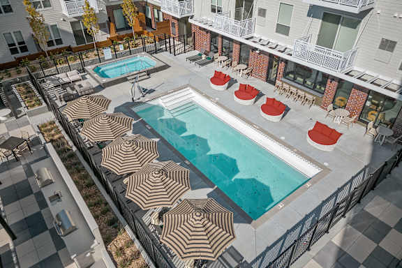 A large outdoor pool surrounded by sun loungers and umbrellas.