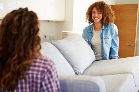 a woman is sitting on a couch and smiling at another woman at The Parker Austin, Pflugerville, 78660