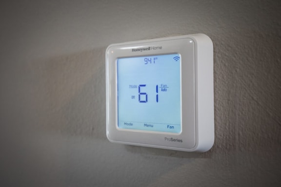 a thermostat on a wall with a digital clock on it