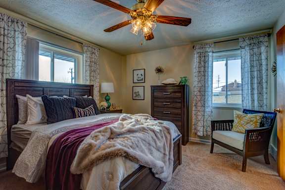 A bedroom with a large bed and a ceiling fan.