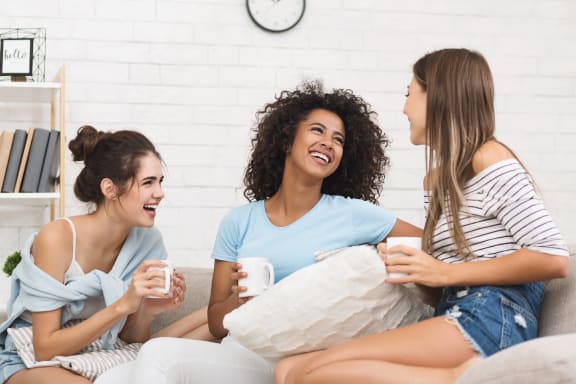 three women sitting on a couch drinking coffee and laughing at Altis Santa Barbara, Naples, 34104
