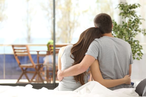 a couple sitting on a bed with their arms around each other