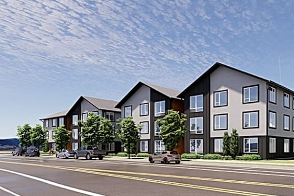A modern apartment building with a car parked in front.