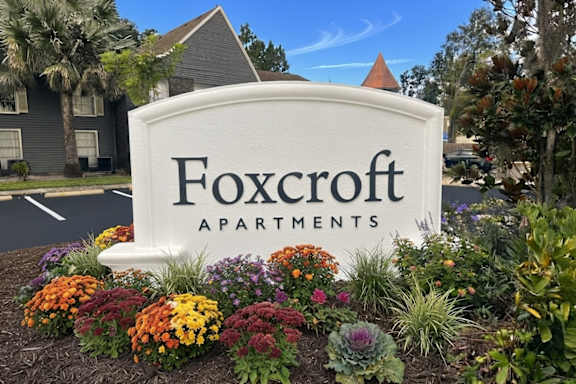 A sign for Foxcroft Apartments is surrounded by flowers.