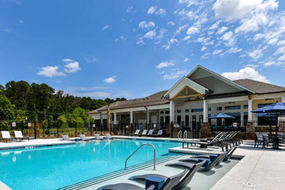 Clubhouse, pool with in water loungers, tables with chairs and umbrellas at Carmel Vista, McDonough