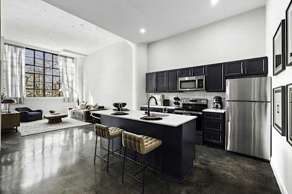 A modern kitchen with a large island and stools.