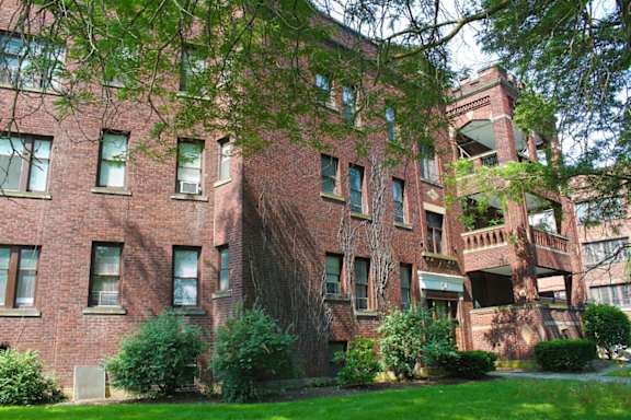 A red brick building with green trees in front.