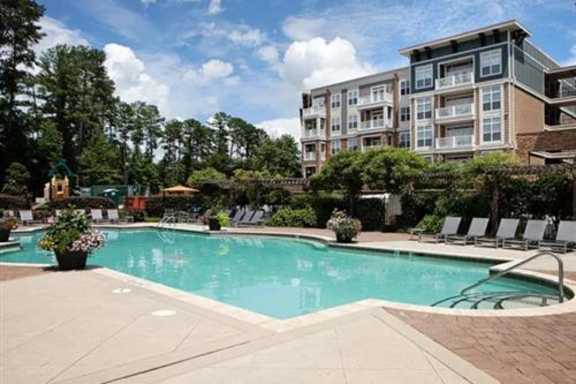 A swimming pool surrounded by lounge chairs and trees.