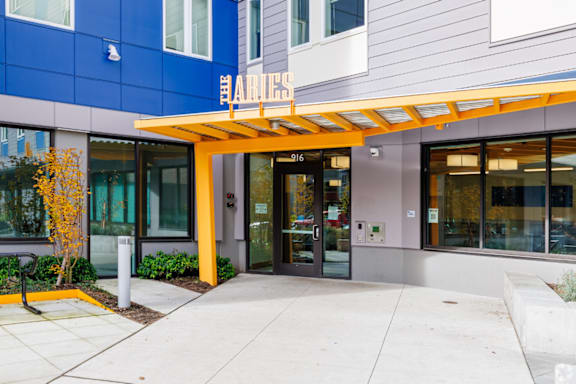 The entrance to a building with a yellow awning and glass doors.