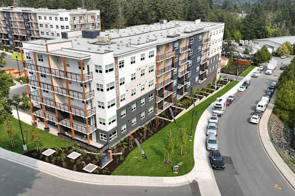 A large apartment complex with a parking lot in front.