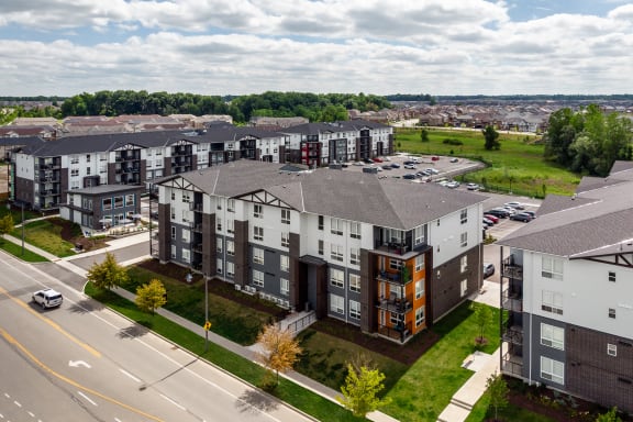 an aerial view of a large apartment complex with a green field in the background