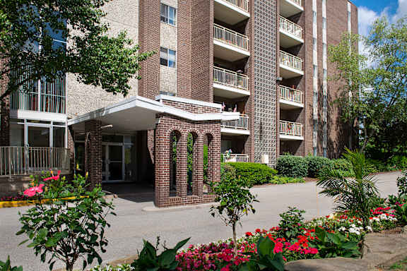 A large brick building with balconies and a walkway in front.