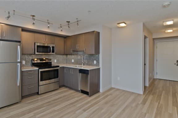 an empty kitchen with stainless steel appliances and wooden cabinets
